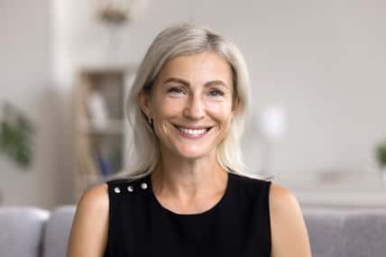 Head shot portrait pretty blonde woman looking at camera, sits alone on sofa photoshooting, enjoy pleasant pastime weekend at home at own or rented apartment. Beautiful mature female profile picture