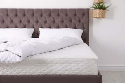 Comfortable bed with new mattress in room. Healthy sleep