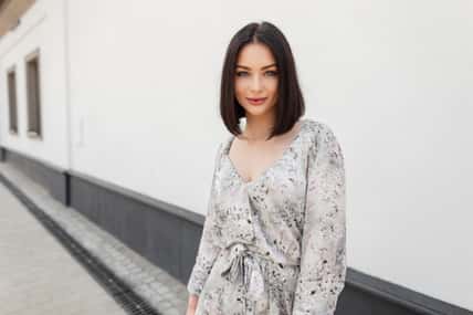 Urban female summer portrait of beautiful woman with hairstyle in fashion spring flowers dress walks in the city