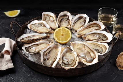 Oysters on a platter. A dozen of fresh oysters with lemon on a dark background