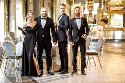 Portrait of an elegant people strictly dressed in black tie standing together at the luxury restaurant hall