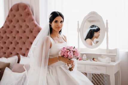 brunette bride in a tight wedding dress in a bright studio
