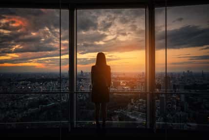 Rear view of Traveler woman looking Tokyo Skyline and view of skyscrapers on the observation deck at sunset in Japan.