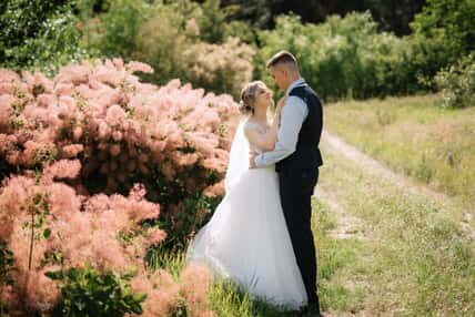 the groom and the bride are walking in the forest on a bright day