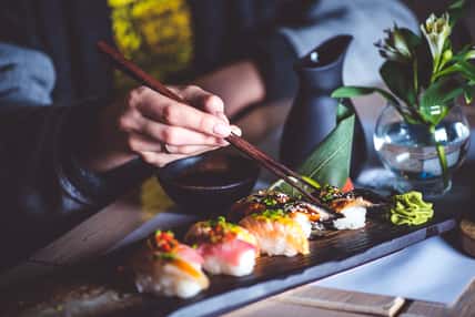 woman eating sushi set with chopsticks on restaurant