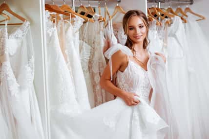 Beautiful bride is trying on an elegant wedding dress in modern wedding salon