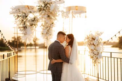 bride and groom against the backdrop of a yellow sunset on a pier near the river
