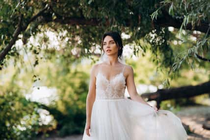 bride blonde girl with a bouquet in the forest in the sunset light