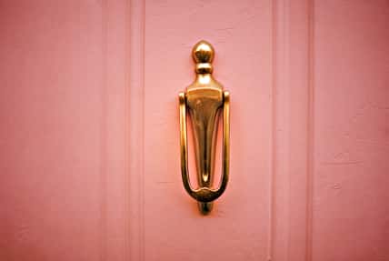 A metal knocker on a wooden door in warm hues