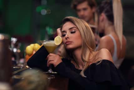 Picture showing young woman sitting alone in bar with a coctail
