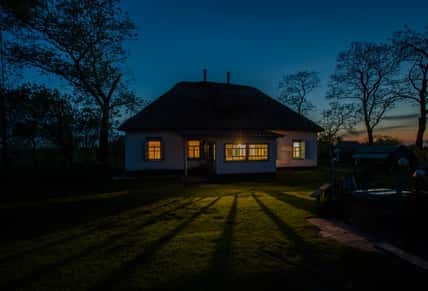 Landscape with a cosy country house at night. Window light. Silhouette of trees. Ukrainian night.
