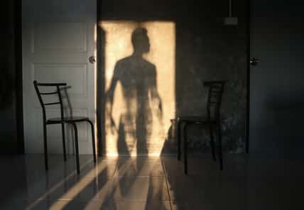 The shadow of the man stood at the door on the wall of the room.