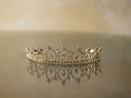A closeup shot of an elegant crown reflected on the glass surface below