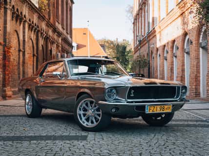 Vintage Ford Mustang GT 1967 parked in the middle of industrial road on a sunny day. American design with alloy wheels. Perfect for marketing, advertising or press articles.