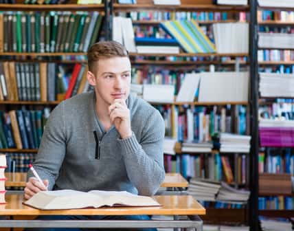 male student with open book working in a library