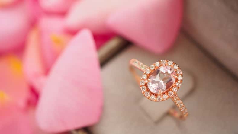 elegant wedding diamond ring in jewelry box on beautiful pink rose petal background close up