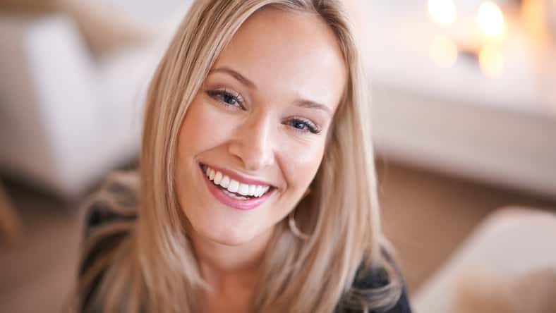 Woman, smile and portrait for relax and happy in home or indoor on weekend and alone on break and joyful. Young person and attractive for peace, rest or chill in living room or house on sofa.