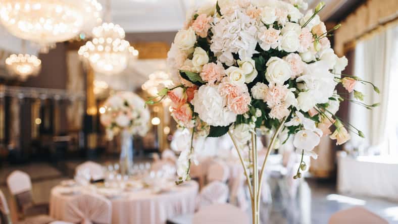 Pink and white wedding bouquet stands in the middle of dinner table
