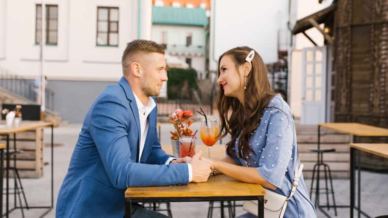 Beautiful couple in love is sitting at a table in an outdoor cafe on a date