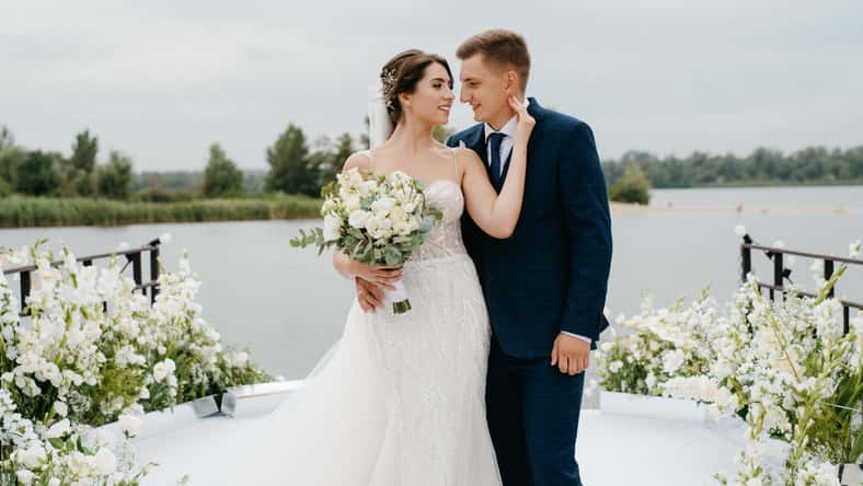 bride and groom against the backdrop of a yellow sunset on a pier near the river