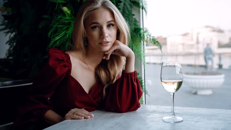 woman with glass of white wine in cafe or restaurant.