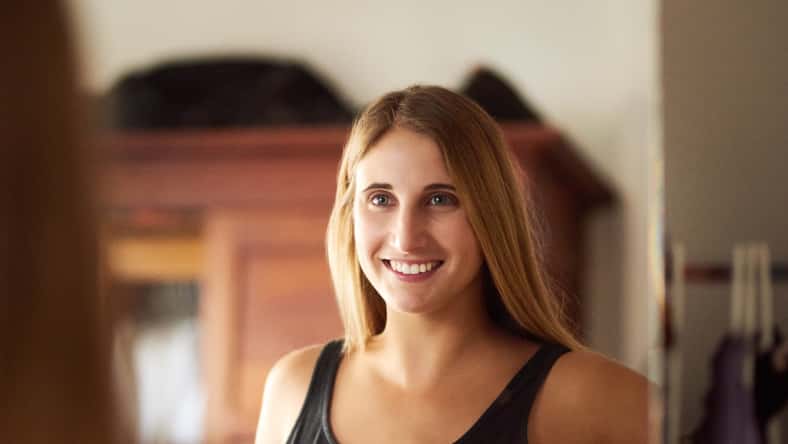 Woman, mirror and reflection in home for dressing, alone and ready in portrait with smile. Female person, glass window or happiness in house with change of clothes, casual or cool in New York City.