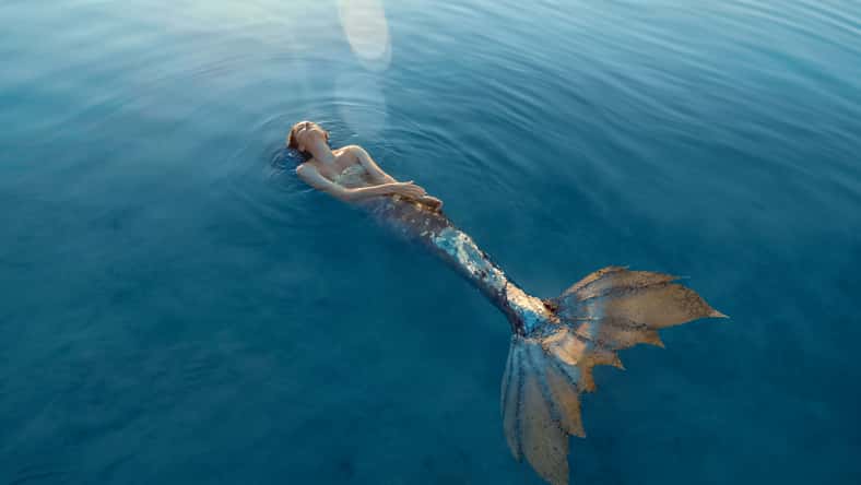 Beautiful redhead woman as mermaid with giant seashell