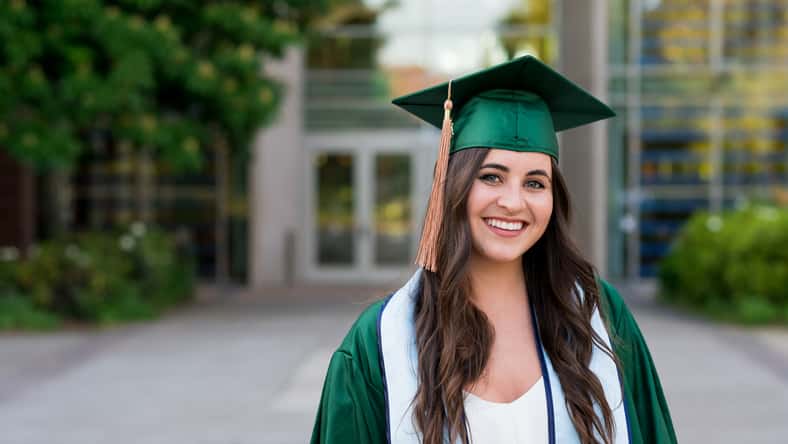 Pretty girl posing for a graduation photo on campus during her senior year of college right before graduation.