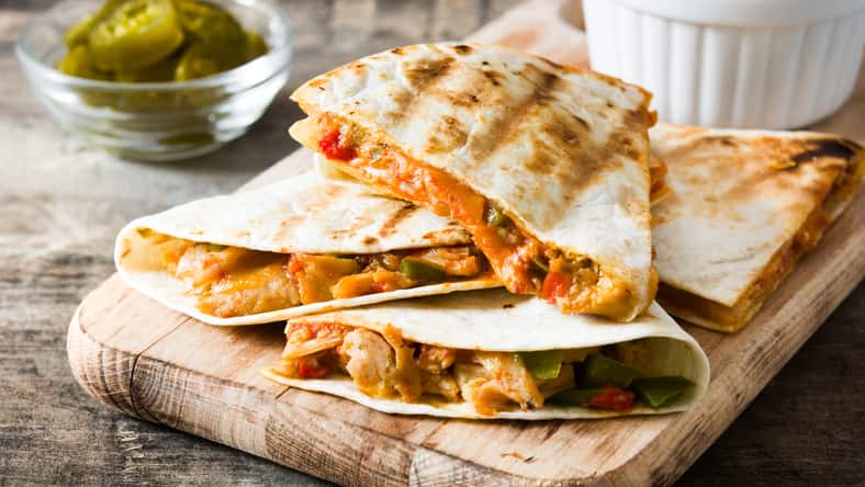 Mexican quesadilla with chicken, cheese and peppers on wooden table.