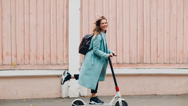 Young woman with electric scooter at the city.