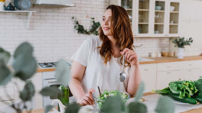 Lifestyle moments of a young woman at home. Woman preparing a salad in the kitchen