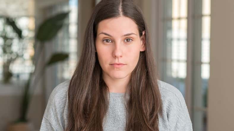Young beautiful woman at home with serious expression on face. Simple and natural looking at the camera.