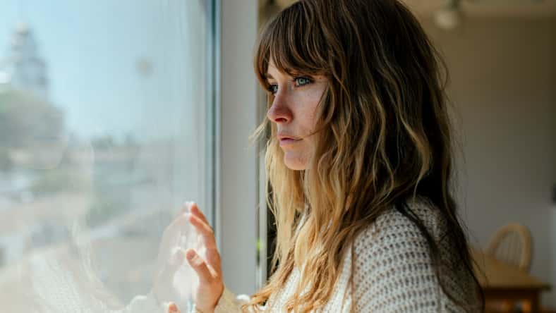 Sad woman staring out the window during a lockdown
