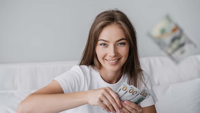 Young woman smiling and holding money.