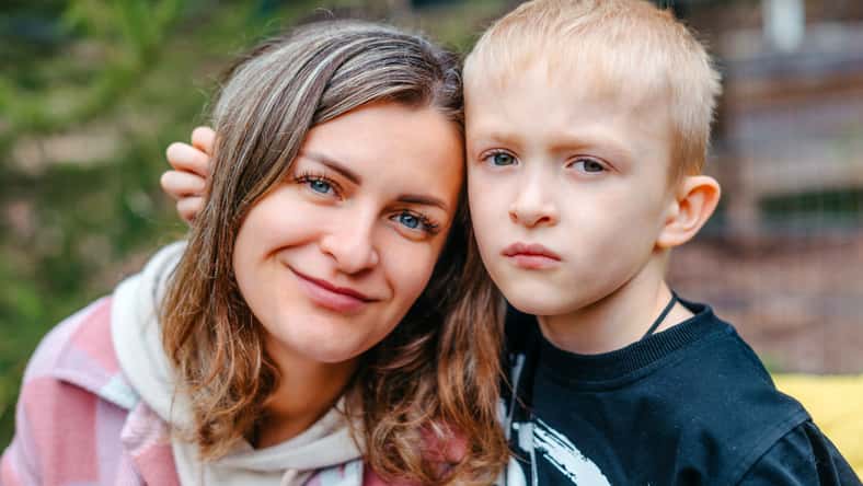 Little boy hugging his mom with a sad expression on his face.