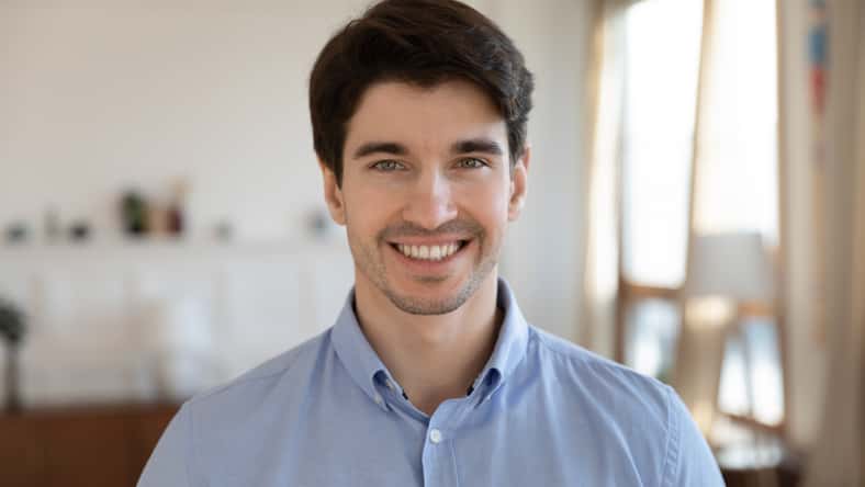 Close up headshot portrait of smiling young caucasian man stand look at camera posing, happy excited millennial male renter or tenant feel positive optimistic about new life, beginning concept