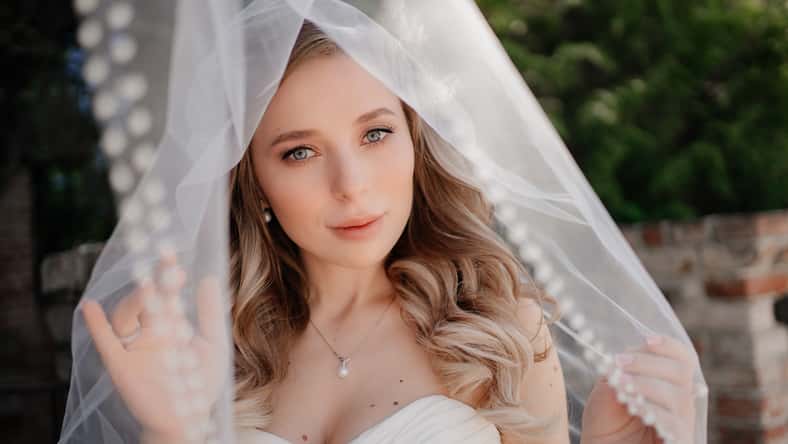 happy bride with long wavy hair under the veil outside. Wedding make-up. wedding planner's services. traditional wedding accessories and merchandise.decorative and caring cosmetics. Natural beauty