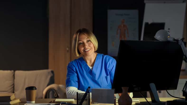 Female nurse working evening shift at table in clinic
