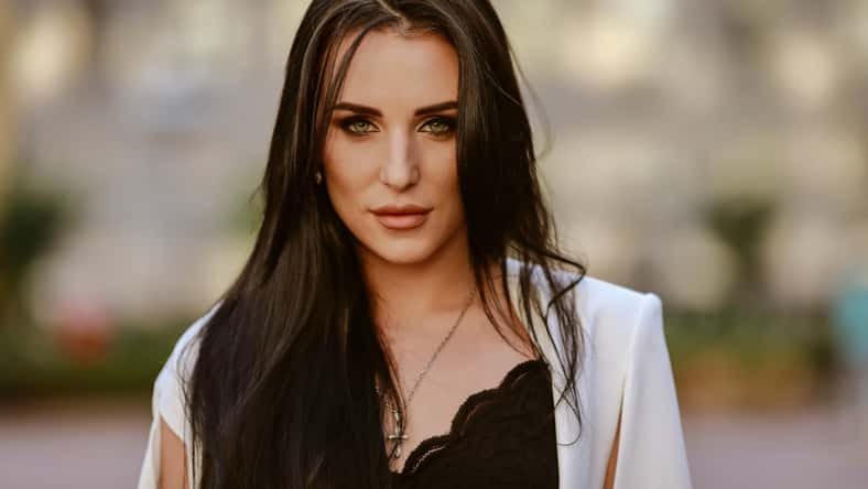 beautiful brunette woman with long hair in a white suit and lace top