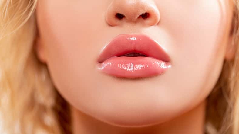 Lips. Beauty injections concept. Close up view of beautiful woman lips with Peachy lipstick. Fashion make up. Cosmetology, drugstore or fashion makeup. Studio shot. Perfect sexy Lips.