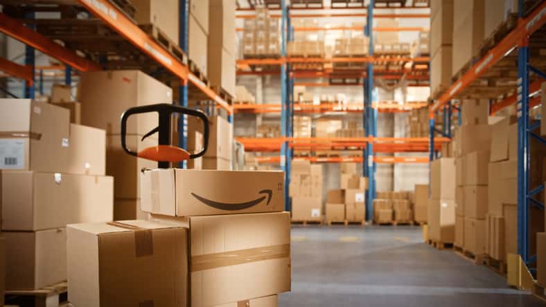 Big Warehouse Package with Amazon Logo Stacked with Cardboard Boxes Ready for Shipment. Logistics Distribution Center for Product Sorting, Customer Delivery