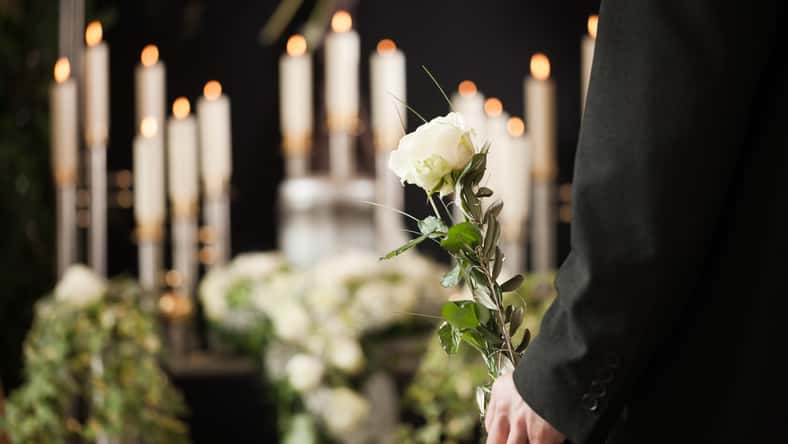 man at funeral with white rose mourning the dead