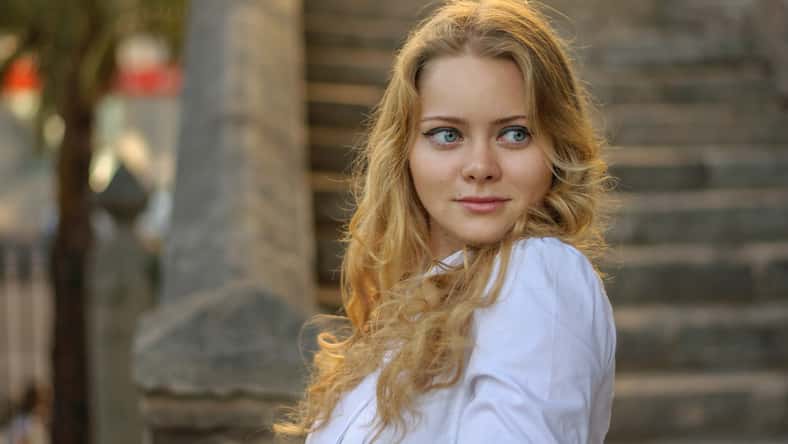beautiful blond woman in white posing, stairs on the background .