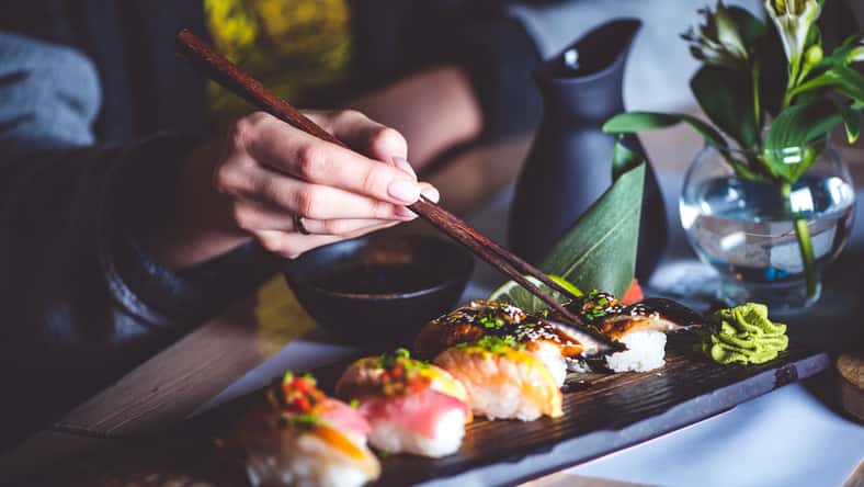 woman eating sushi set with chopsticks on restaurant
