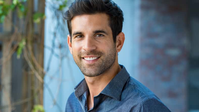 Handsome mid adult man smiling and looking at camera. Portrait of happy young casual man. Close up portrait of hispanic guy standing outdoor.