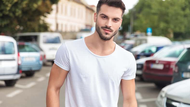 portrait of young casual man with ring in ear standing in a street in a city, outdoor picture