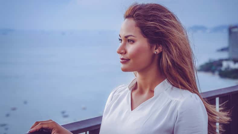 Portrait of young female model on the rooftop of a restaurant in Pattaya with ocean and city skyline in the back.