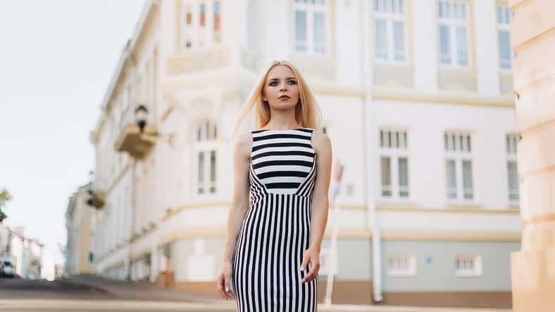 Street portrait of young beautiful blodie caucasian stylish girl walking along the streets in summer warm day