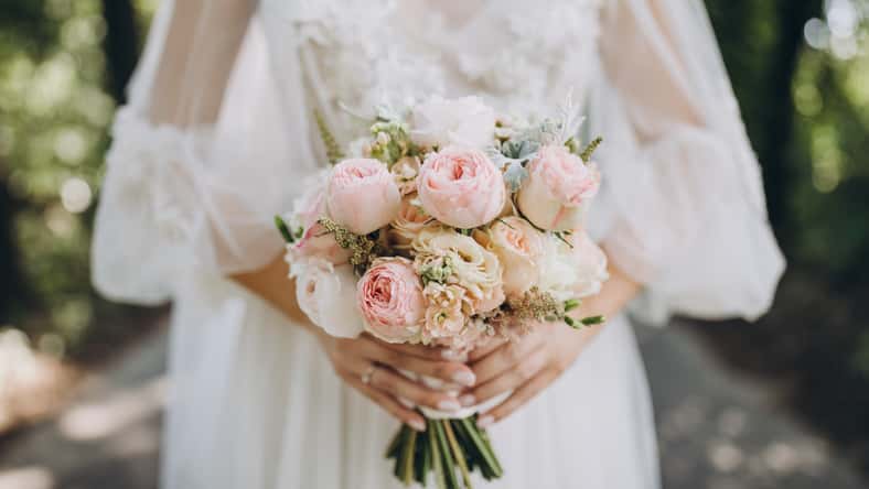 bride in a white wedding dress holding a bouquet of roses, peonies and greenery