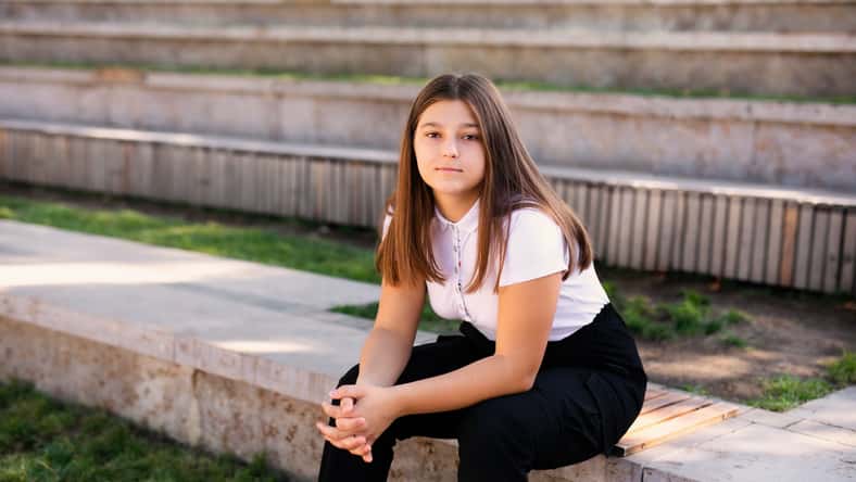 Closeup of teenage girl sitting on a school bench.
